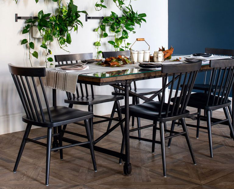 A photograph of the Hugh chair in natural finish, with a clear view of its classic Windsor style design, paired with a rustic farmhouse table.